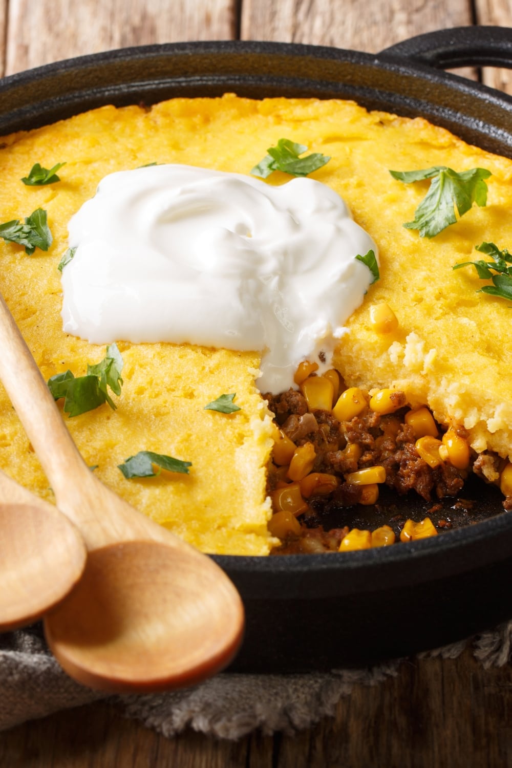 Tamale pie made with cornbread, ground beef and corn, topped with cream cheese on cast iron. 