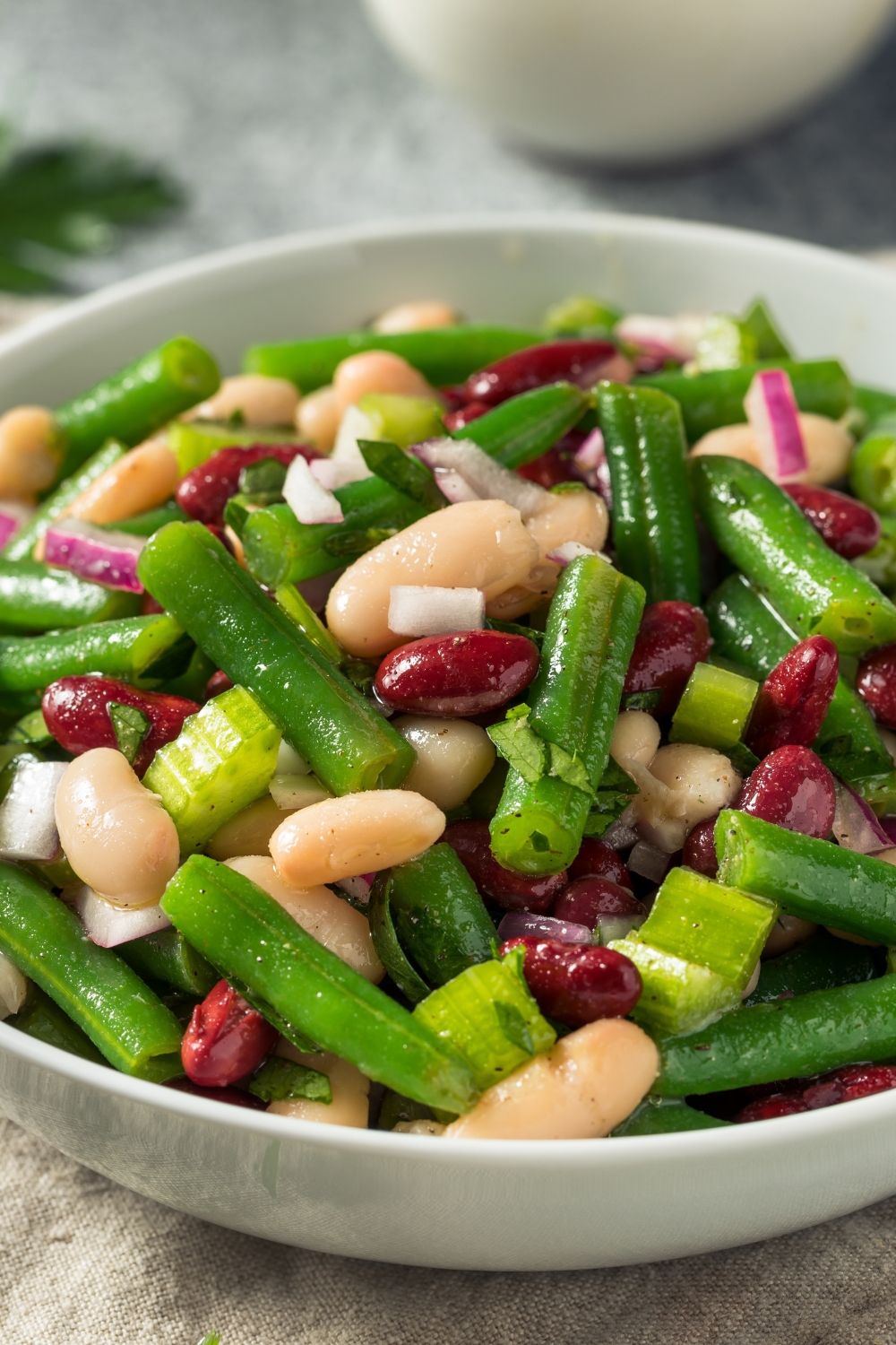 A bowl of three bean salad made with red, white and green beans, sliced celery and seasoning. 