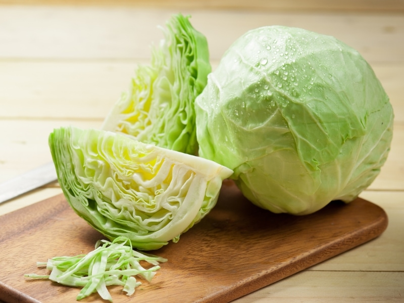 Whole and Sliced White Cabbage on Chopping Board