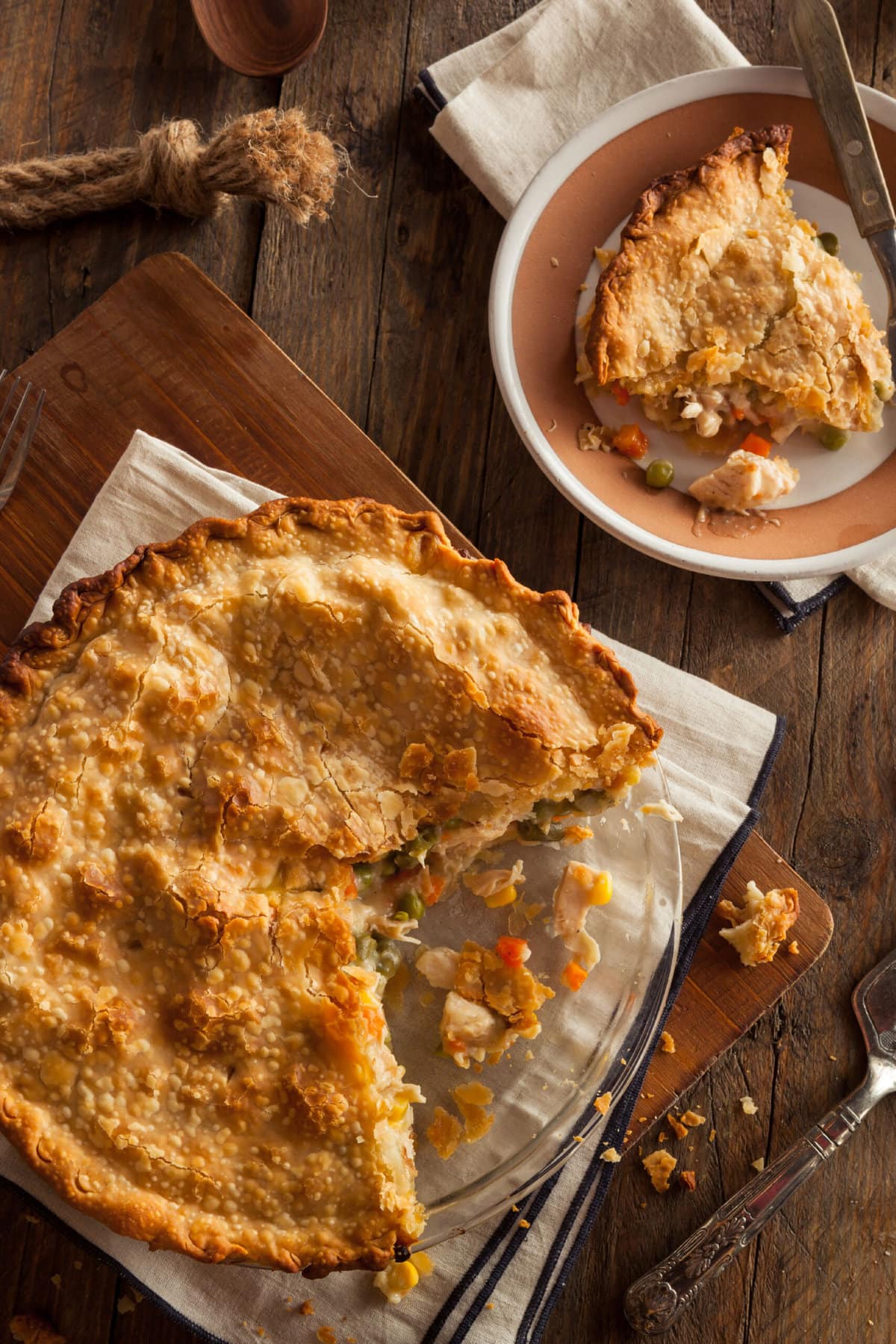 Chicken pot pie whole and slice on top of a wooden table. 