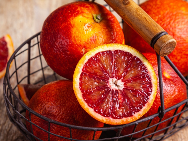 Blood Oranges Whole and Sliced in a Metal Basket