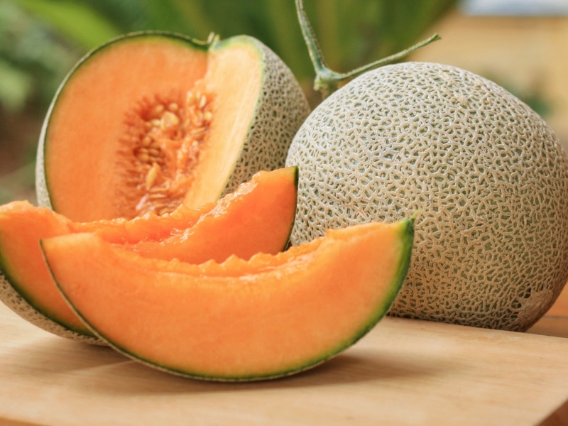 Cantaloupes Whole and Sliced on a Wooden Table