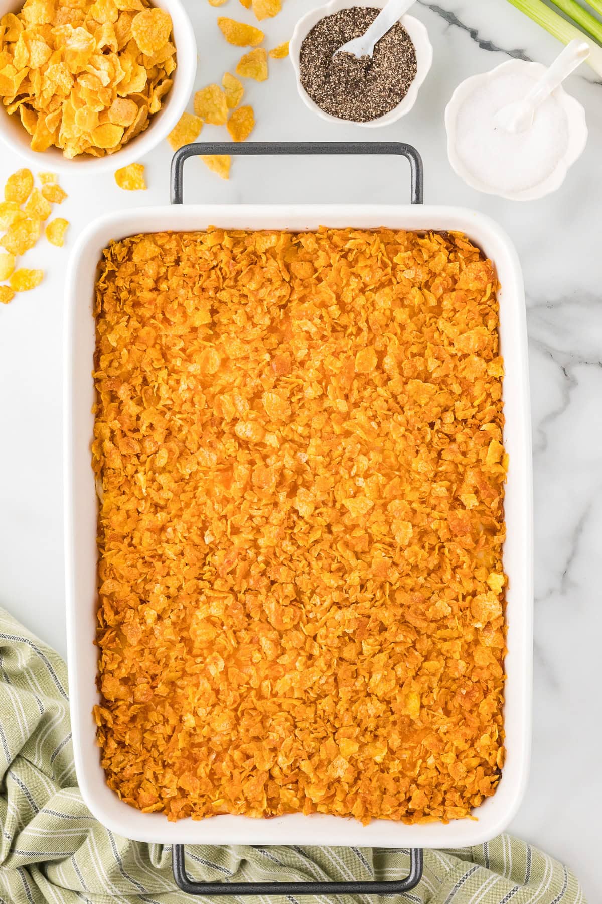 Cheesy potato casserole topped with crushed cornflakes in a baking dish