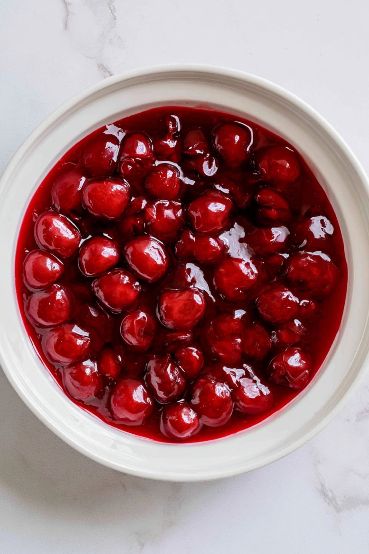 An overhead view of cherry pie filling in a bowl.