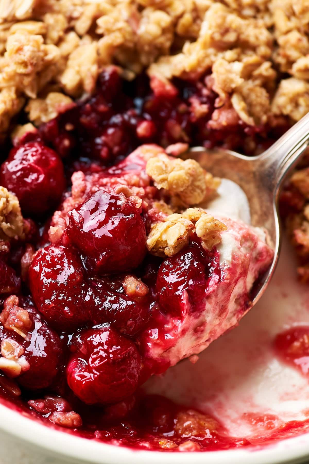 A close-up of spoonful of cherry crisp with ice cream. 