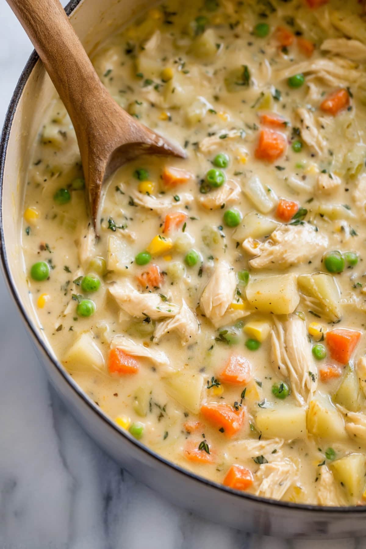 Chicken pot pie soup with mixed vegetables, potatoes and corn in a Dutch oven.