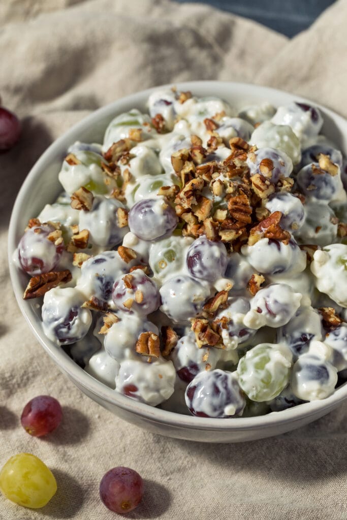 Bowl of Creamy Grape Salad Garnished With Chopped Pecans