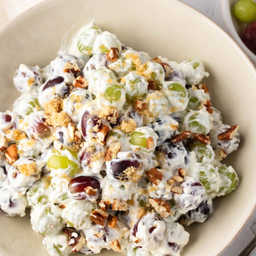 A serving of creamy grape salad with nuts and sugar, top view