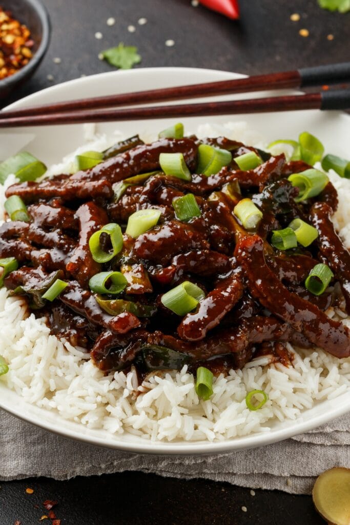 Homemade Mongolian Beef with Rice and Green Onions in a White Plate