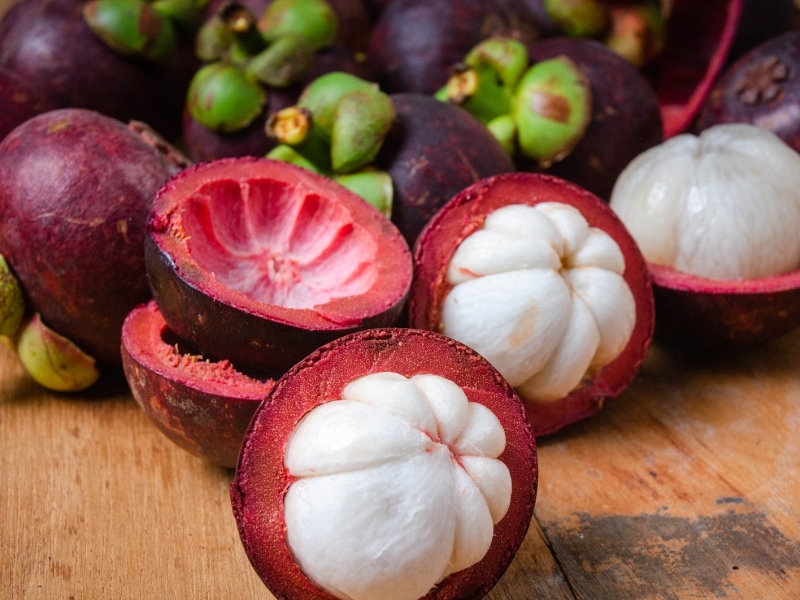 Mangosteen Whole and Peeled on a Wooden Table