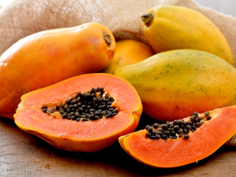 Papaya Whole and Sliced on a Wooden Table