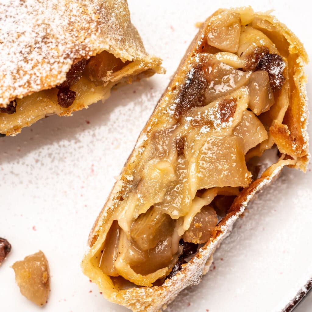 Slice of apple strudel on the side with apples and raisins in the middle