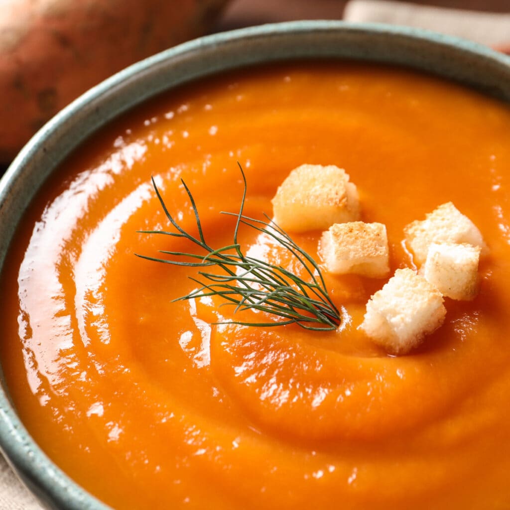 Tasty Sweet Potato Soup With Bread Slices and Herbs Garnish