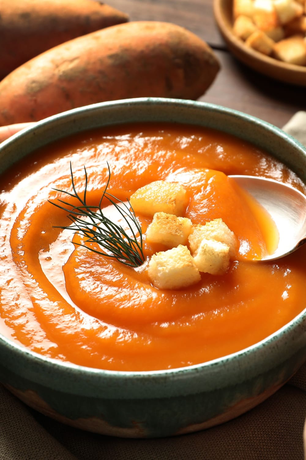 A bowl with sweet potato soup garnished with croutons. 