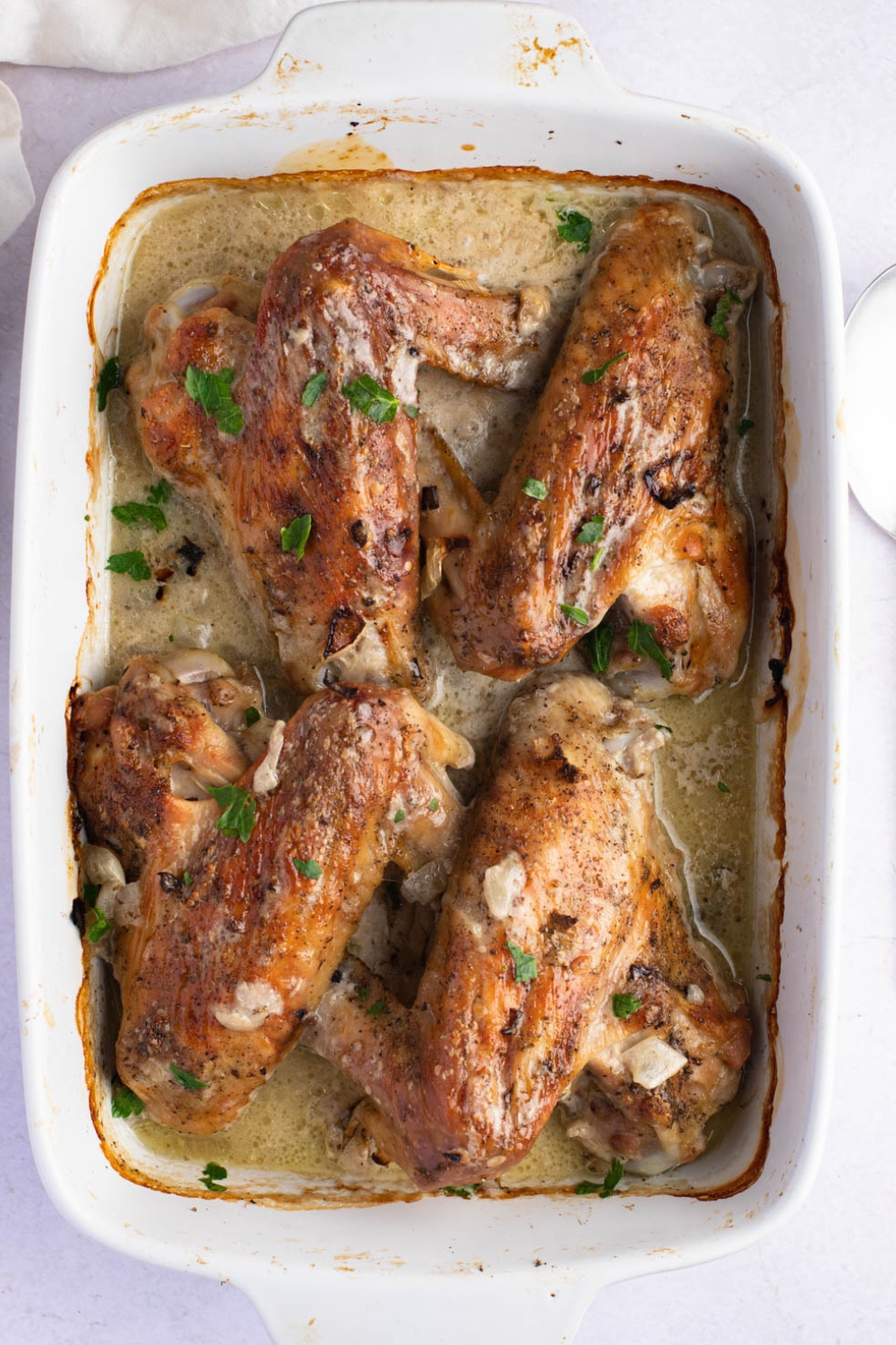 Baked turkey wings in a white baking dish. 