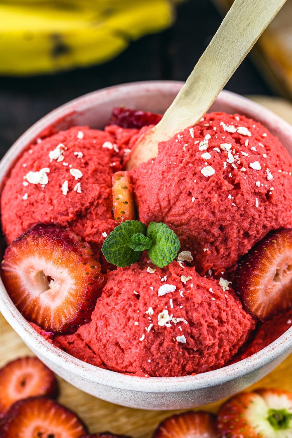 Closeup of cold sweet strawberry ice cream in a bowl garnished with sliced strawberries and cheese. 