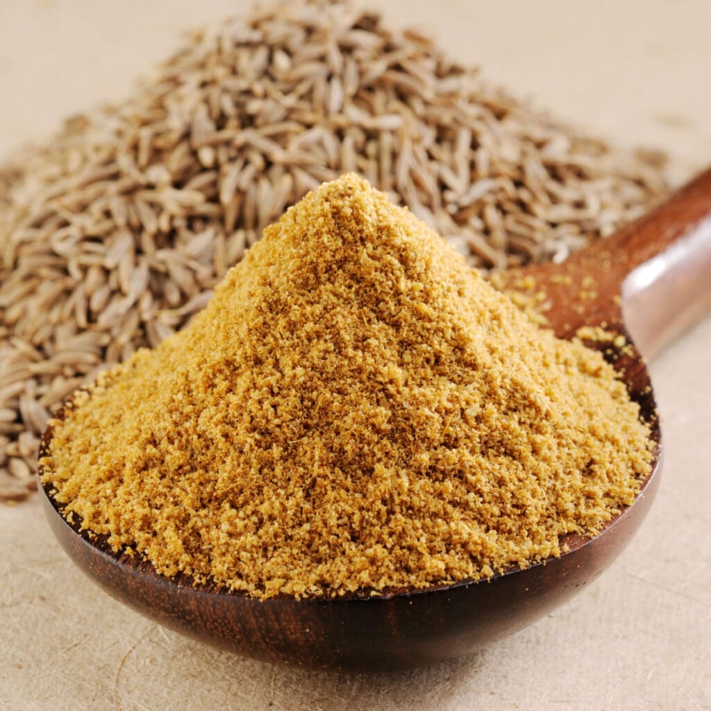 Heap of Ground Cumin in a Wooden Spoon