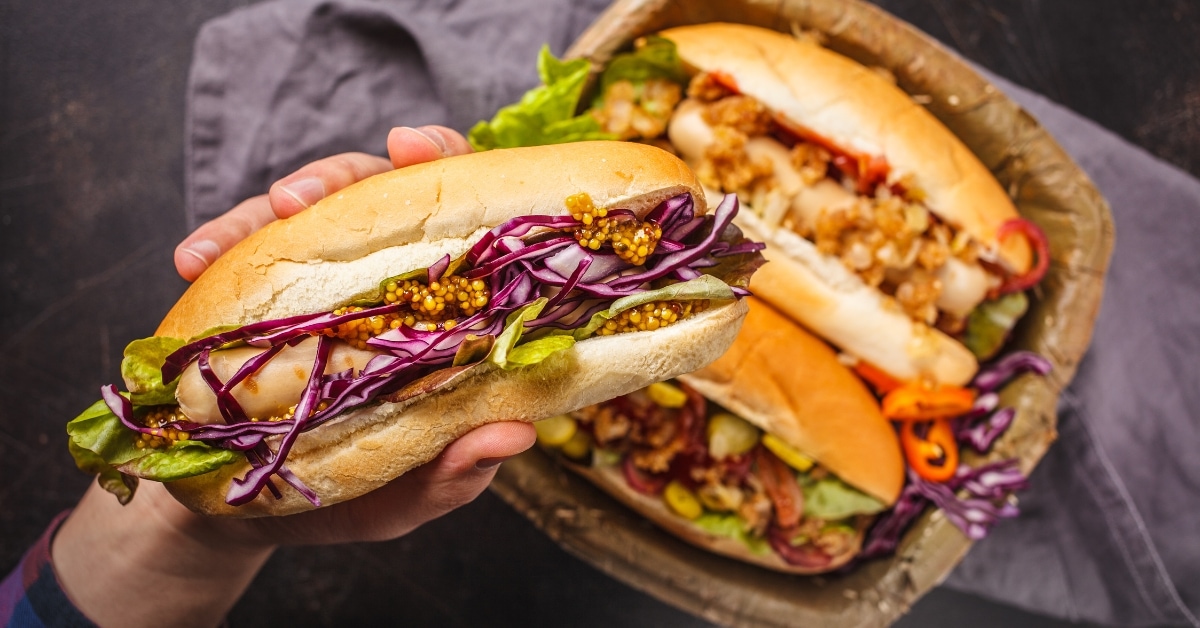 Holding a Chili Dog with Red Cabbage, Lettuce and Spices