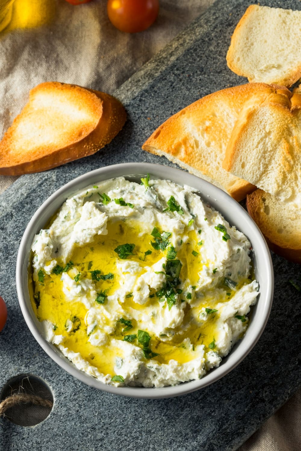 Goat cheese dip with garlic and parsley, served with slices of bread.
