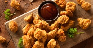 Homemade Popcorn Chicken with Ketchup in a Wooden Board