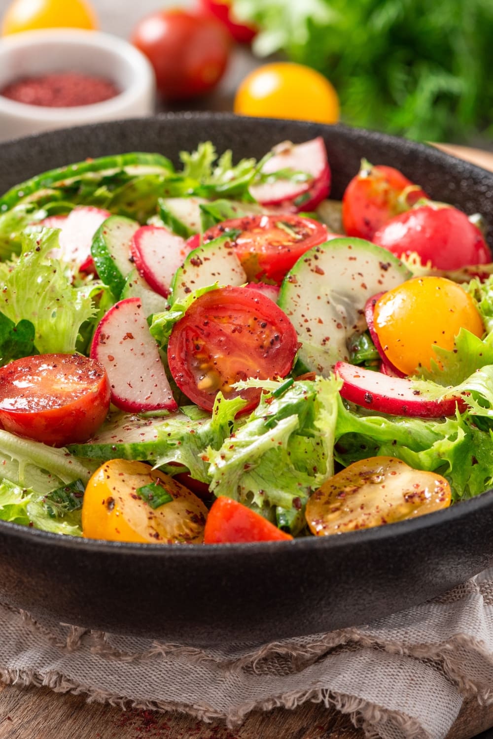 A Bowl of Vegetable Salad with Tomatoes, Radish, Lettuce and Cucumber Seasoned With Chili Powder and Pepper