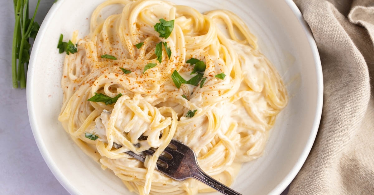 Homemade Creamy and Flavorful Noodles Romanoff with Herbs in a White Plate