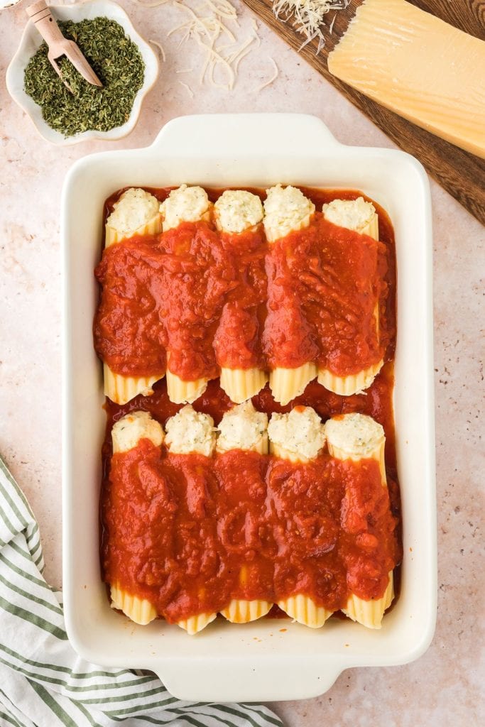 Cheese stuffed manicotti covered with marinara sauce in a baking dish, top view