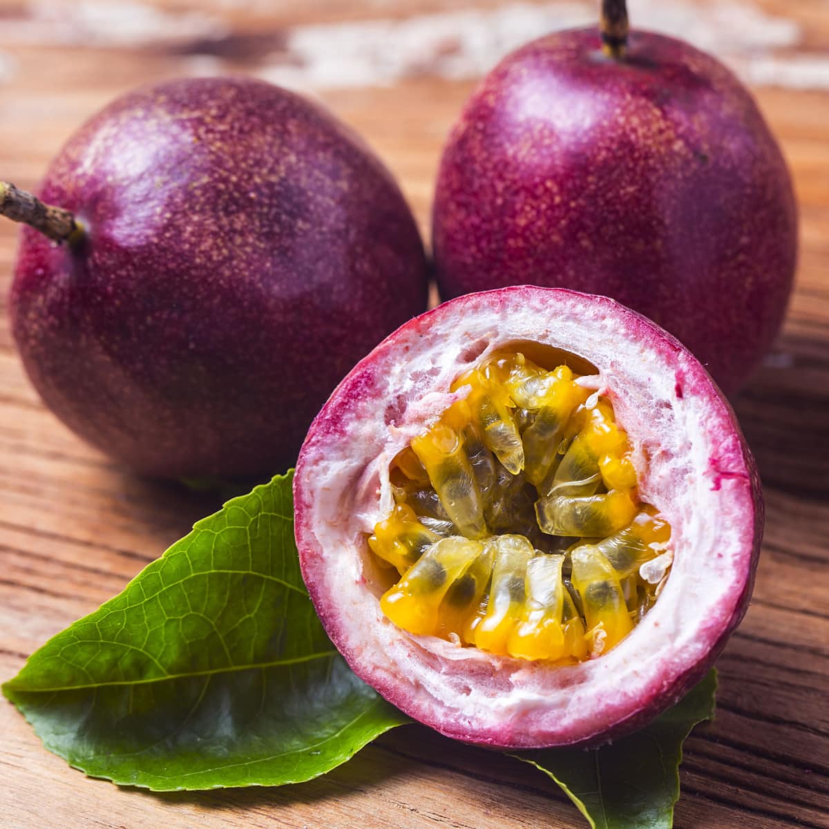 Whole and Sliced into Half Ripe Passion Fruit on a Wooden Table