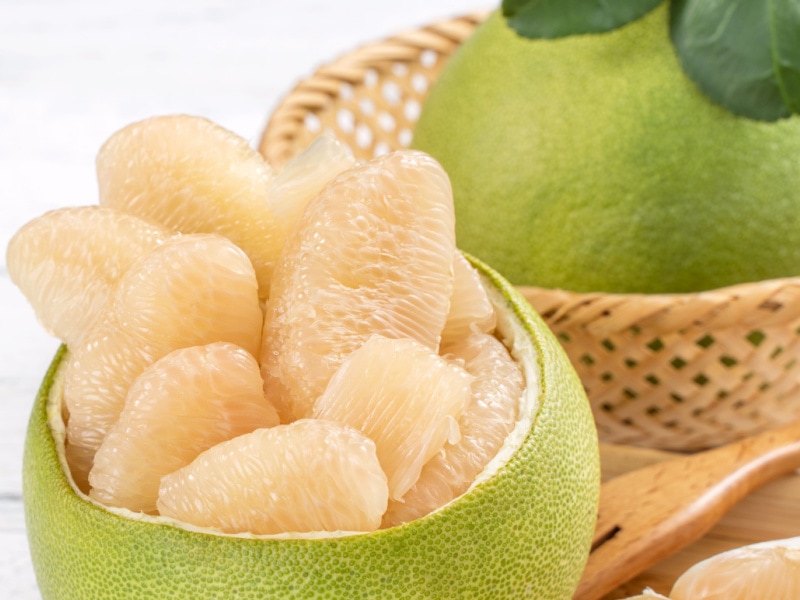 Pomelo (Suha) Whole and Peeled in a Wooden Background