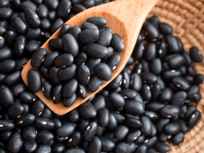 Raw Black Beans in a Basket and Wooden Spoon