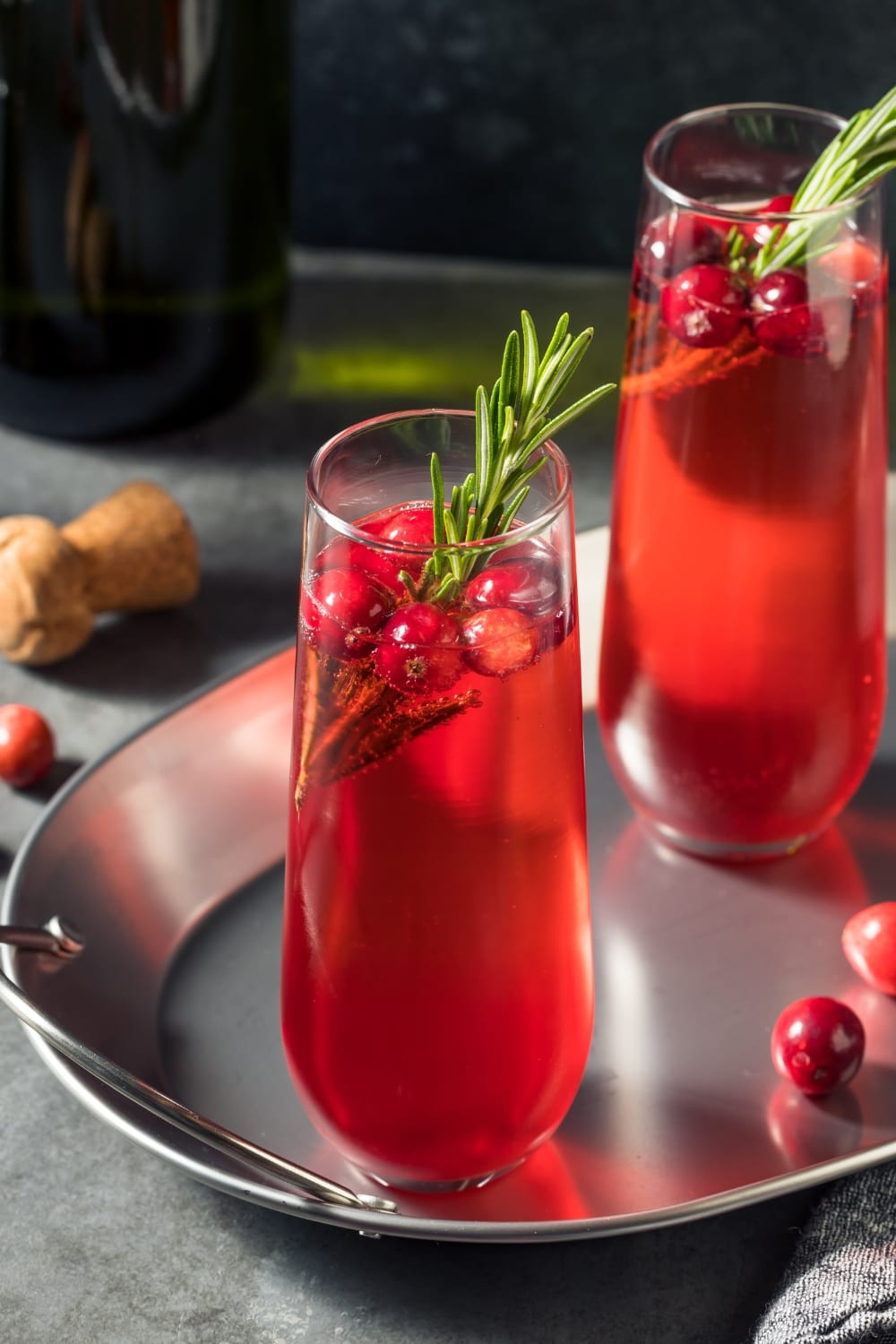 Two Glasses of Boozy Poinsettia Cocktail Garnished with Cranberry and Prosecco