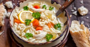 Bowl of Chicken Orzo Soup with Carrots and Lemons