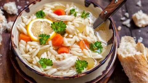 Bowl of Chicken Orzo Soup with Carrots and Lemons