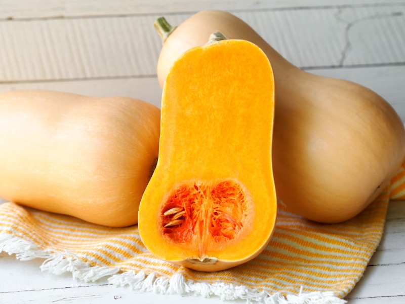 Two Whole and Half Butternut Squash on Top of a Cloth