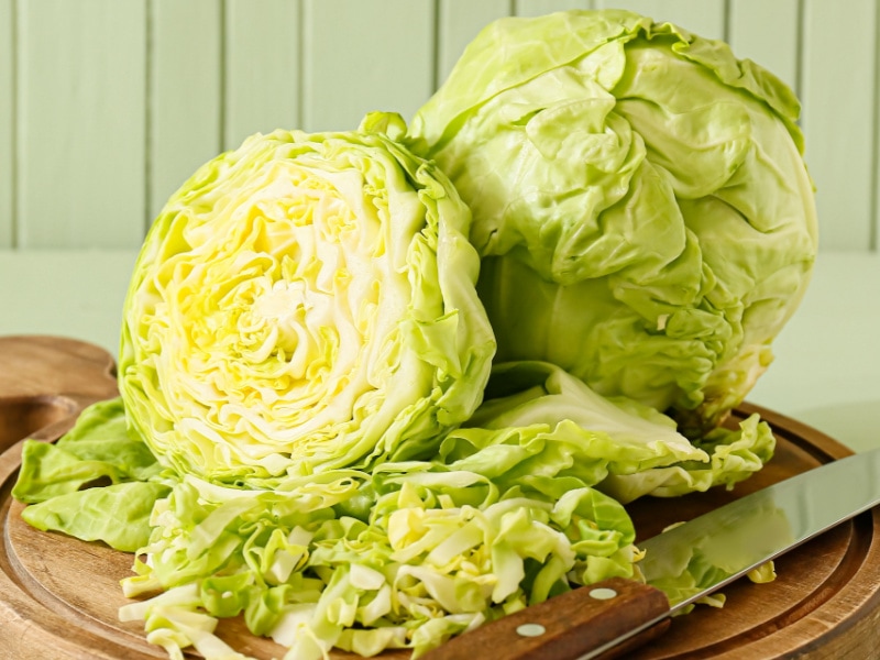Whole and Slice Cabbage on a Wooden Cutting Board