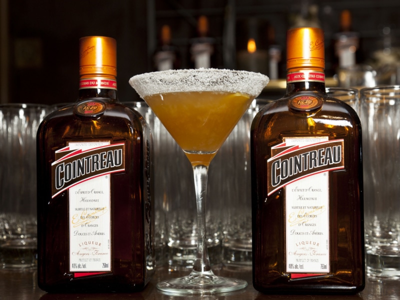 Two bottles of cointreau and a cocktail in the middle.