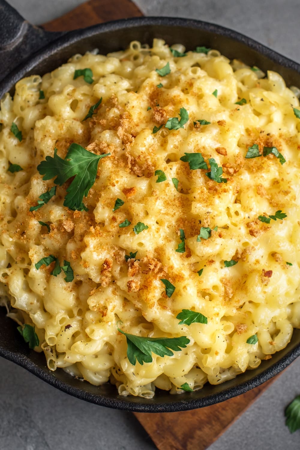 Top view of a bowl of mac and cheese topped with melted cheese and chopped parsley. 
