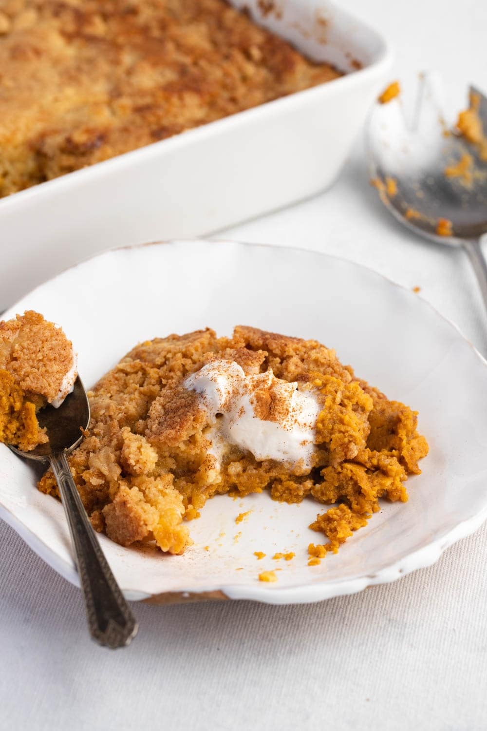 Serving of pumpkin cobbler on a plate with spoon. 