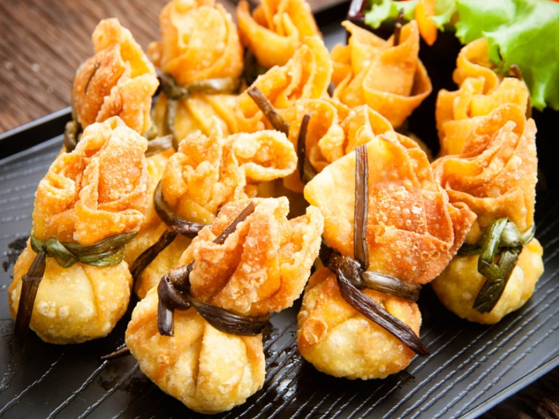 Bunch of Fried Wontons on a Wooden Plate