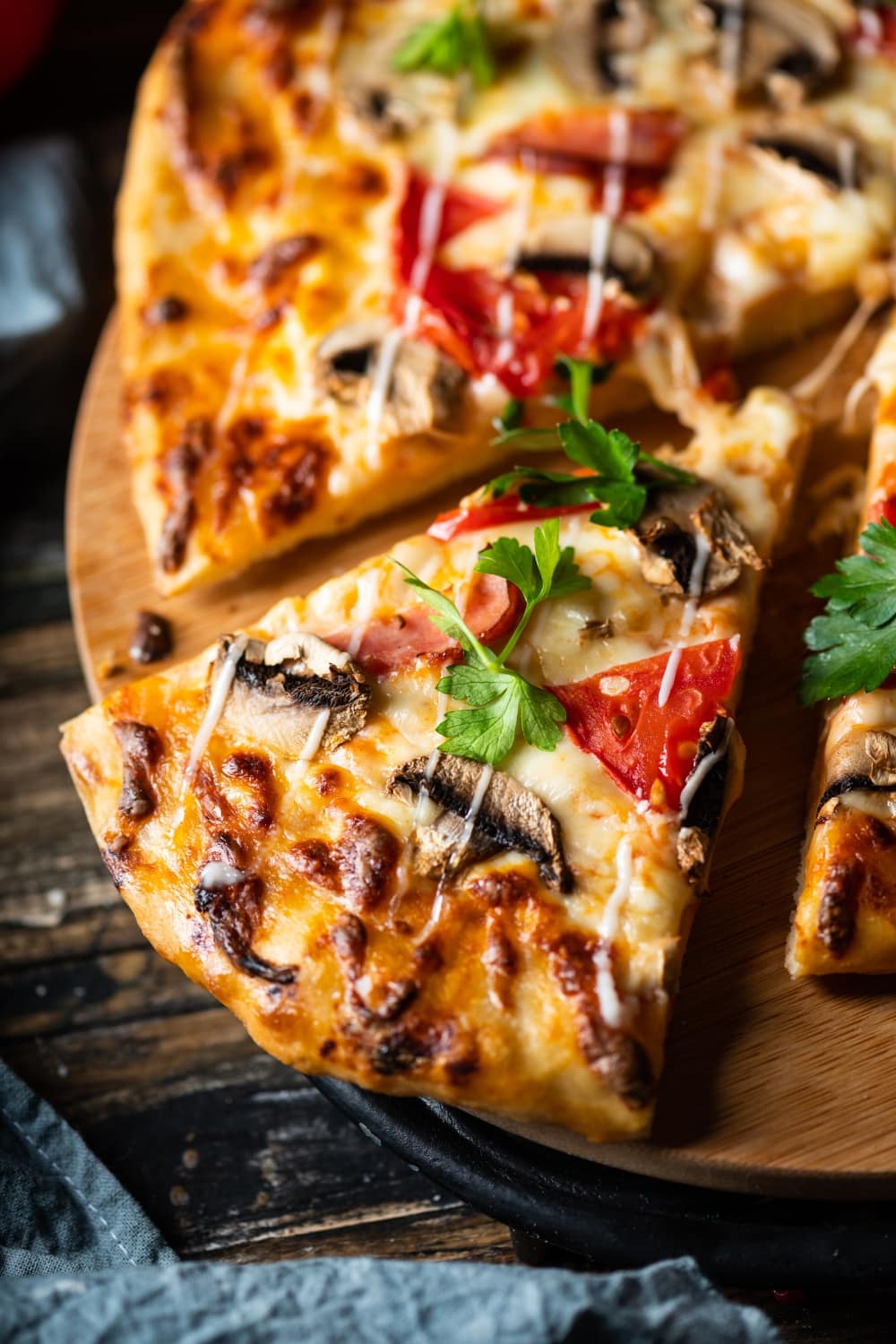 Sliced Grilled Pepperoni Pizza with Mushrooms, Mozzarella and Tomatoes Served on a Wooden Pizza Board