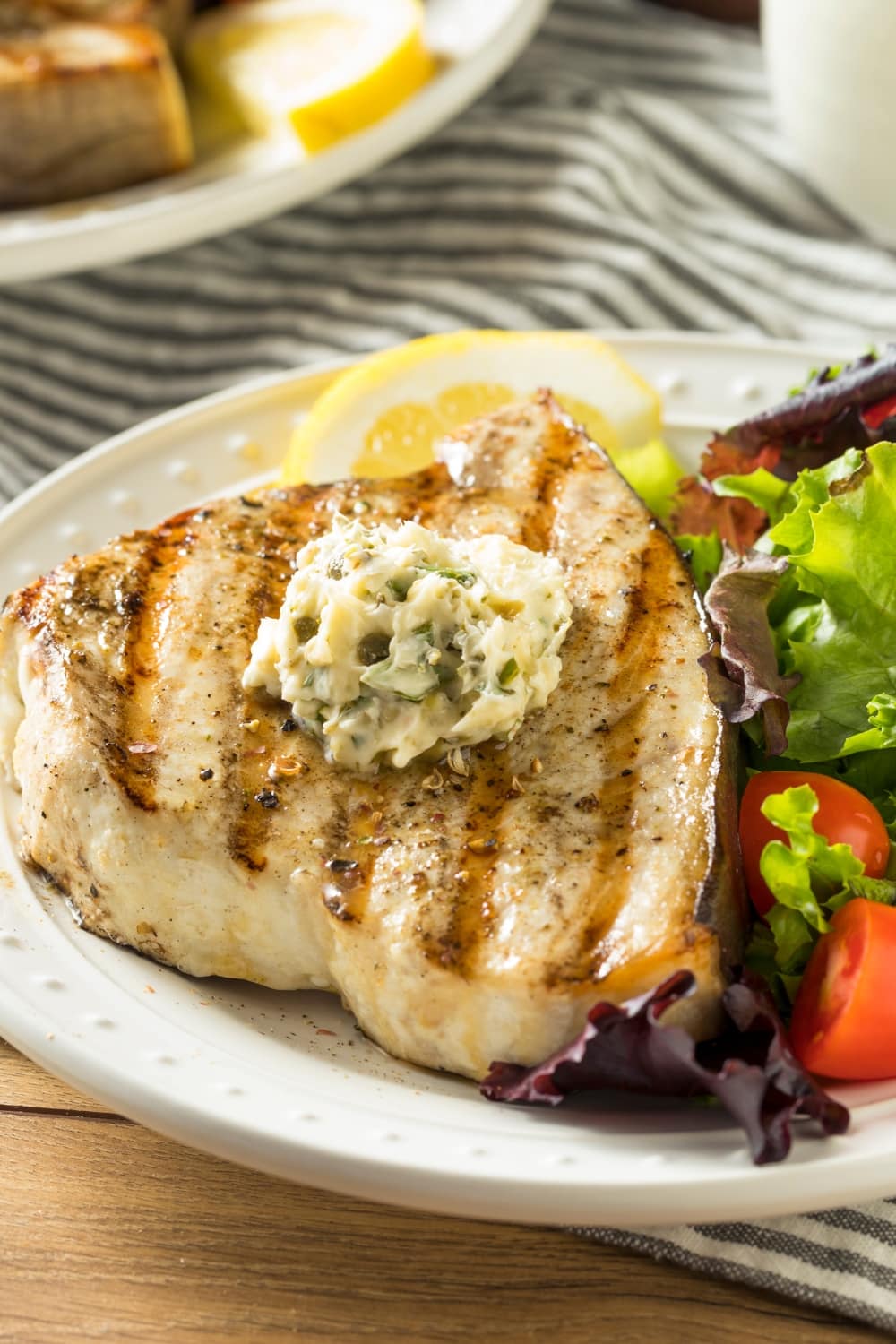 Grilled swordfish steak with vegetable salad on the sides. 