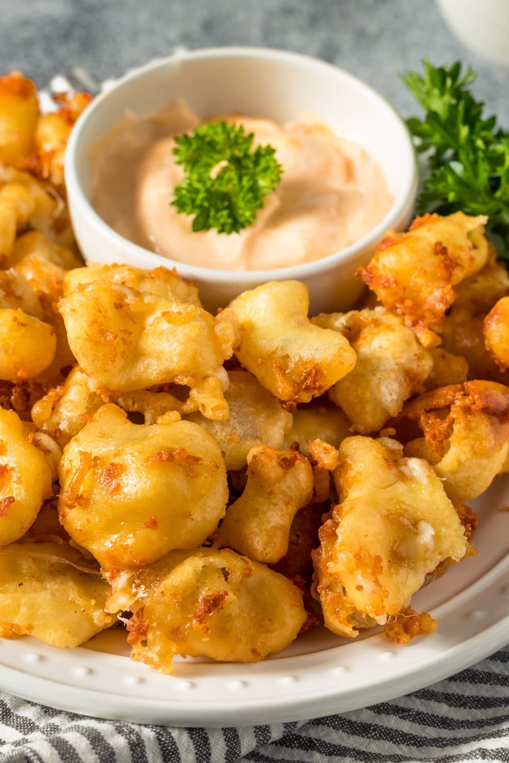 Bite Size Cheese Curds with Dipping Sauce on a Small Bowl in the Middle of the Plate