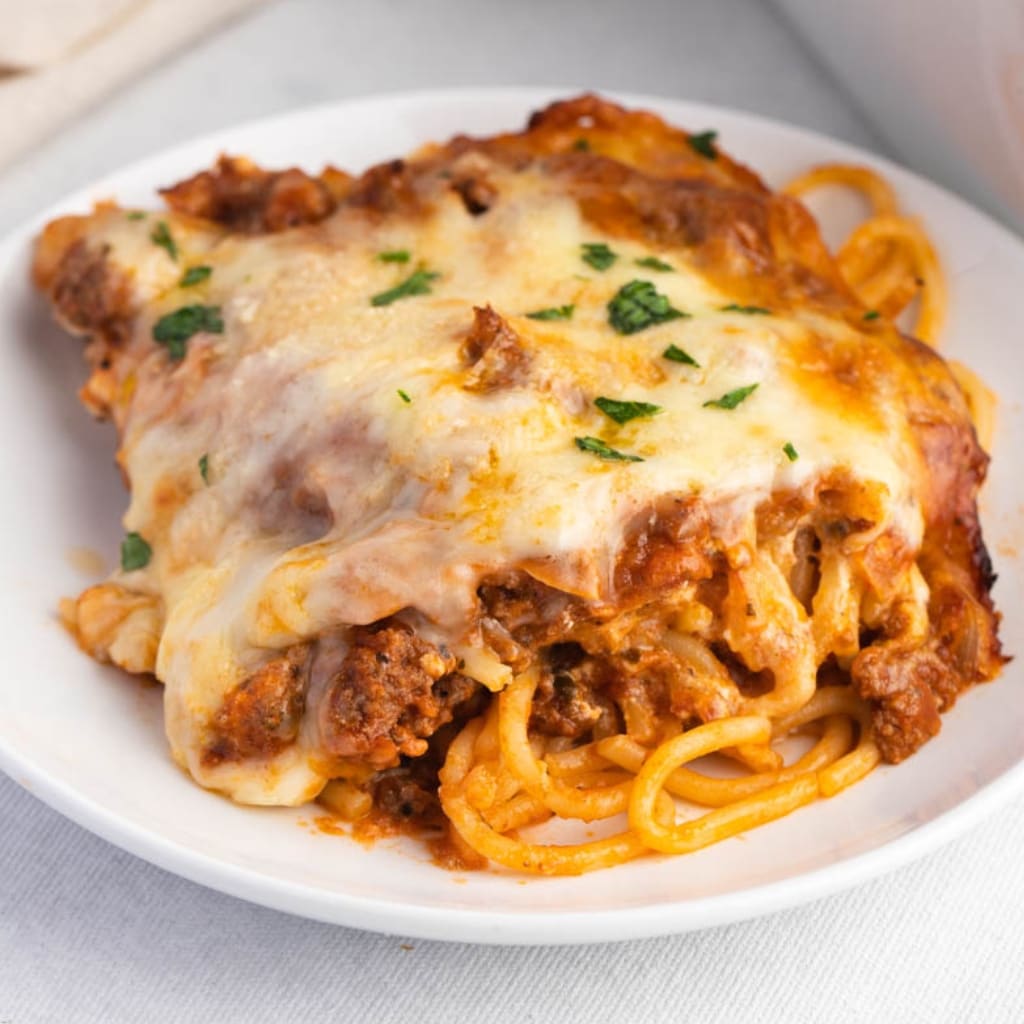 Portion of Homemade Million Dollar Spaghetti with Ground Beef and Cheese Served on a White Plate
