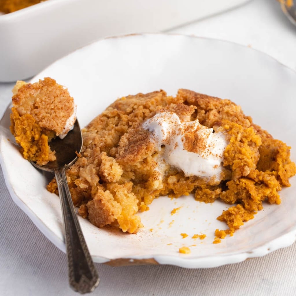 Pumpkin Spice Cobbler Topped With Fluffy Whipped Cream Served on a White Saucer