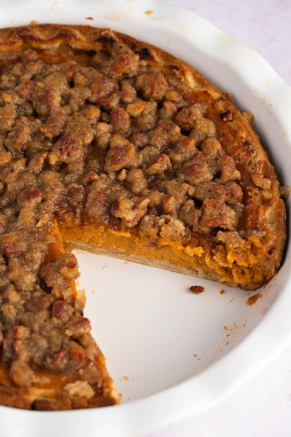 Sweet Potato Pecan Pie with a slice taken out cooked on a white baking dish. 