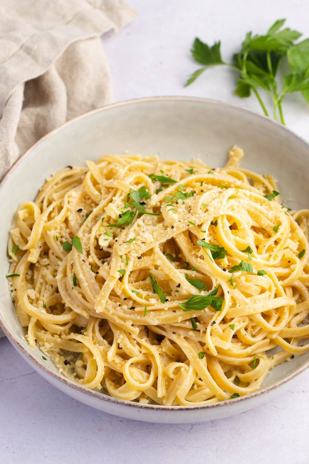 Buttered noodles on plate served with parmesan cheese.