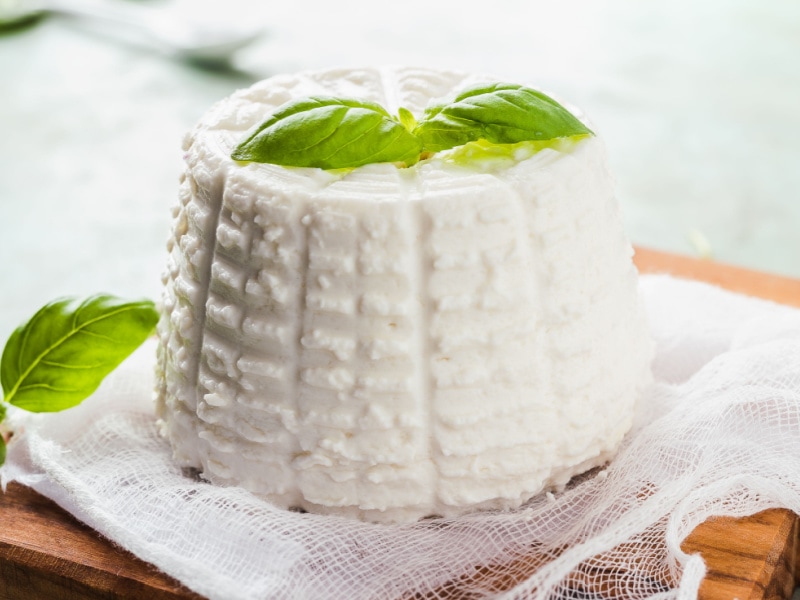 Fresh Ricotta Cheese with Basil on Top on a Wooden Cutting Board