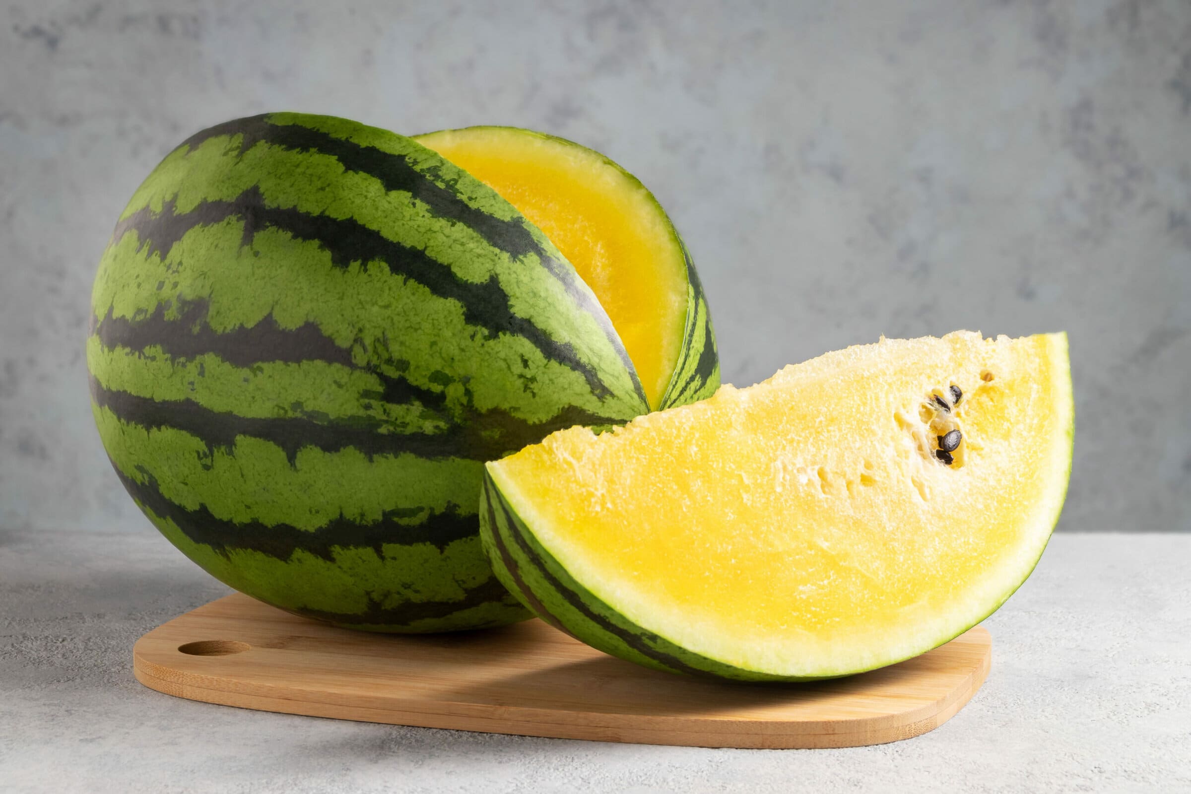 Whole Ripe Yellow Watermelon Sliced Placed on Top of Wooden Cutting Board