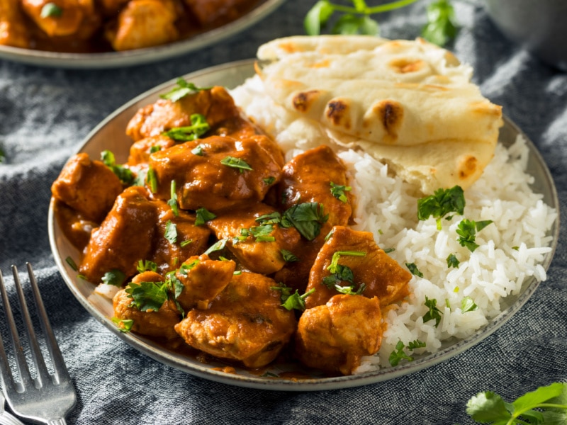 Tikka masala served with rice and naan on a bowl. 