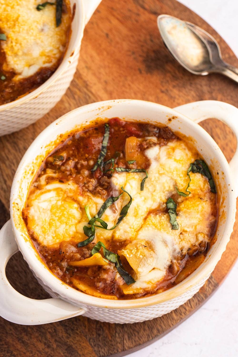Bake Lasagna Soup with ground beef, tomato sauce and cheese served in a round casserole on a wooden board
